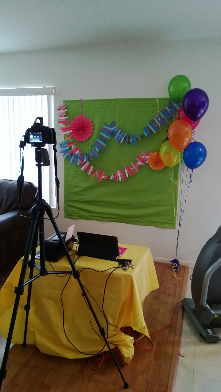 Early DIY photo booth setup with green backdrop and balloons